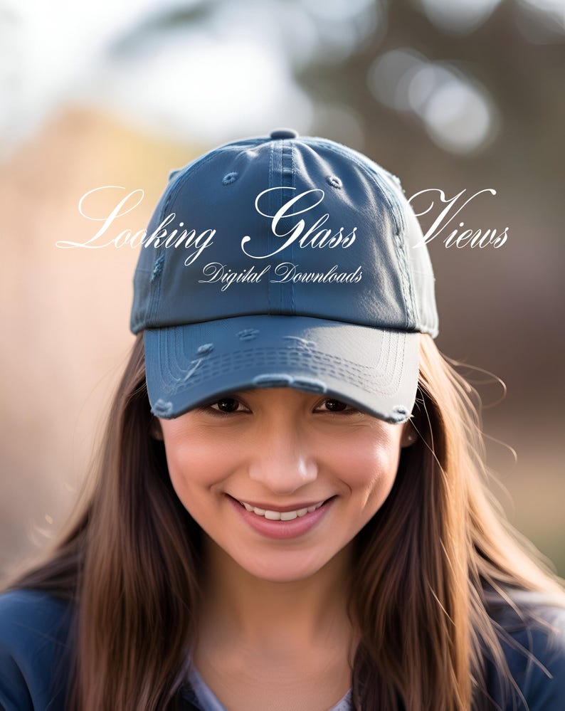 May include: A blue distressed baseball cap with the text "Looking Glass Views" and "Digital Downloads" in white. The cap is worn by a person with long brown hair.