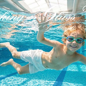 May include: A young child wearing swim goggles and white shorts swims underwater in a pool. The image has the text "Looking Glass Views" in the upper left corner. The pool has blue tiles and a white border.