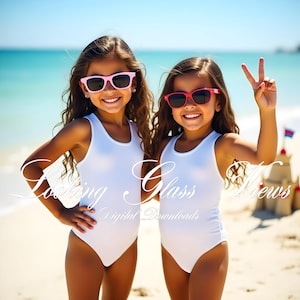 Op de afbeelding: Twee jonge meisjes in witte tankini-badpakken en zonnebrillen op een strand. De meisjes glimlachen en kijken naar de camera. De tekst "Looking Glass Views Digital Downloads" is over de afbeelding gelegd.