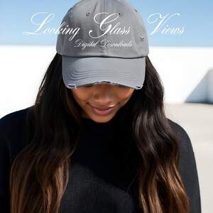 May include: A grey distressed baseball cap with the text "Looking Glass Views Digital Downloads" on the front.