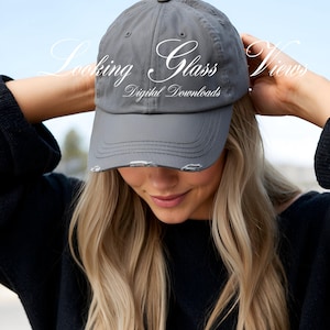 May include: A gray baseball cap with distressed edges and the text "Looking Glass Views Digital Downloads" in white.