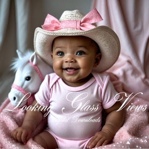 May include: A baby girl wearing a pink and white cowboy hat with a pink bow. The baby is sitting on a pink blanket and smiling. The text "Looking Glass Views Digital Downloads" is visible in the image.