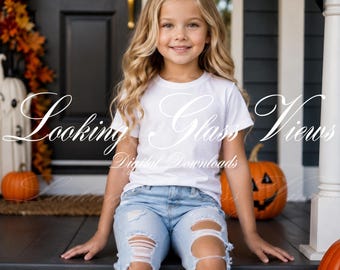 Può includere: Una t-shirt bianca a maniche corte abbinata a jeans in denim azzurro consumato con grandi strappi sulle ginocchia e sulle cosce. L'immagine include una filigrana con il testo Looking Glass Views Digital Downloads.