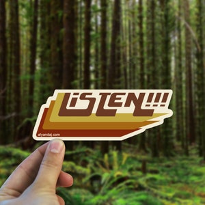 May include: A retro-style sticker with the word "LISTEN!" in brown, orange, and yellow letters on a white background. The sticker has a slightly rounded shape and a white border.