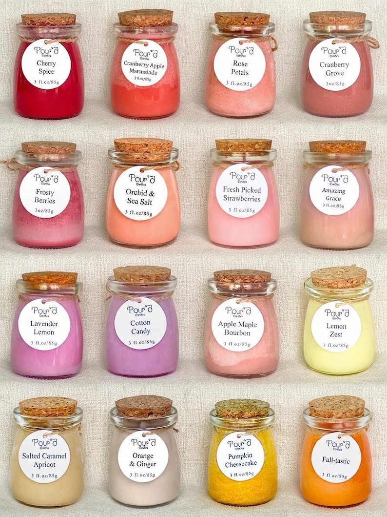 May include: Sixteen small glass jars filled with colored wax, each topped with a cork stopper. Each jar features a white circular label with the text Pour'd Earth, a scent name, and 3 fl. oz/85g. The scents include Cherry Spice, Cranberry Apple Marmalade, Rose Petals, Cranberry Grove, Frosty Berries, Orchid & Sea Salt, Fresh Picked Strawberries, Amazing Grace, Lavender Lemon, Cotton Candy, Apple Maple Bourbon, Lemon Zest, Salted Caramel Apricot, Orange & Ginger, Pumpkin Cheesecake, and Fall-tastic.