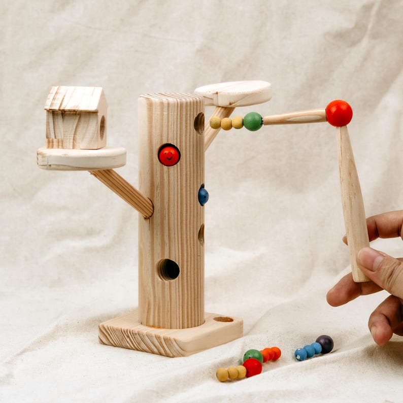 Toddler using magnetic stick to catch worms from wooden Montessori tree toy game