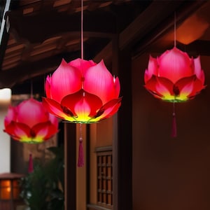 Puede incluir: Tres linternas de papel en forma de flor de loto de color rojo y amarillo que cuelgan del techo. Las linternas están decoradas con un borde amarillo alrededor de los bordes.