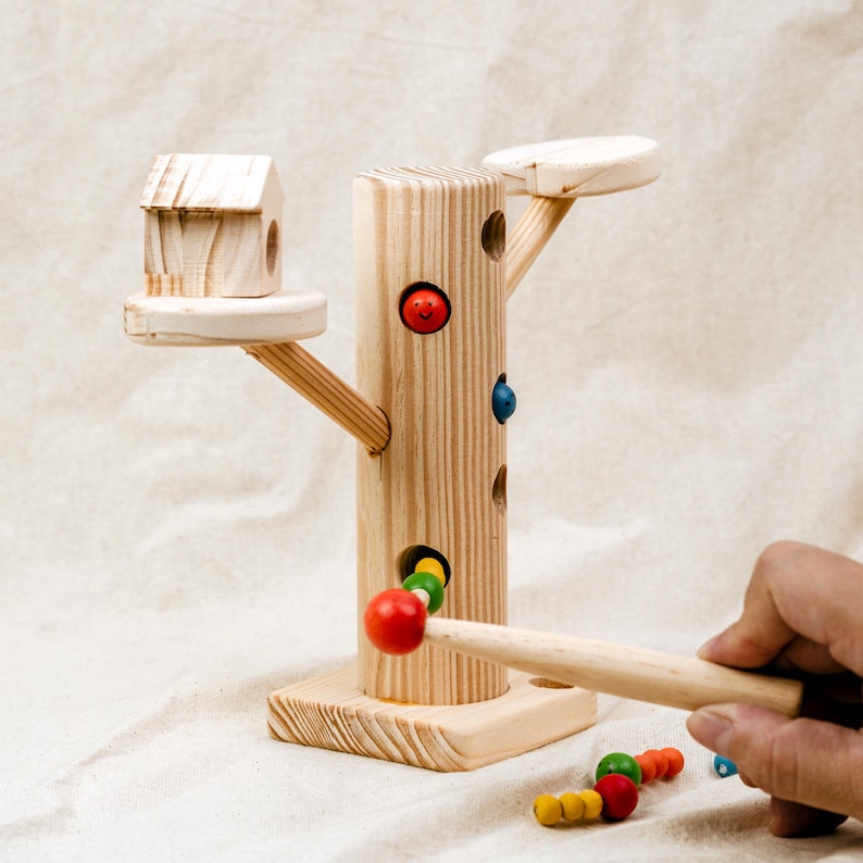 Child playing with magnetic worm catching toy featuring wooden tree and removable colorful worms