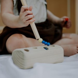 Toddler playing with wooden magnetic worm toy, improving fine motor and hand-eye coordination.