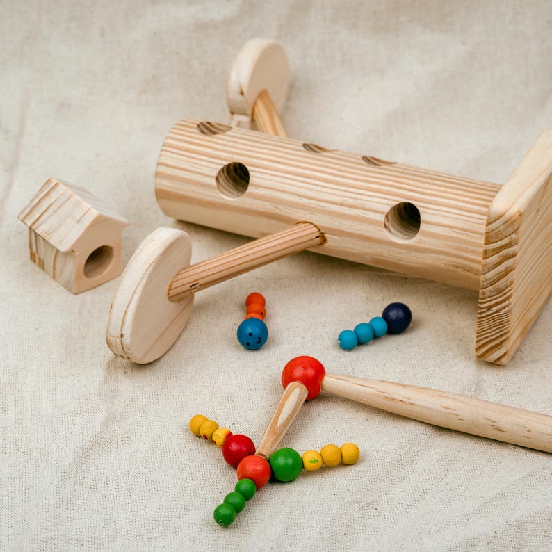Wooden log magnetic worm catching toy with colorful worms and magnetic stick on neutral background