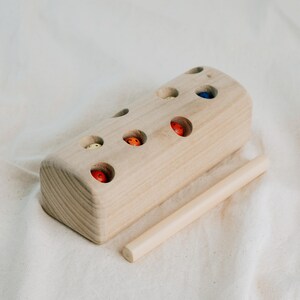 Wooden Montessori toy block with colorful worms placed in holes for magnetic catching.