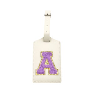 May include: White leather luggage tag with a purple felt letter A with gold glitter accents.