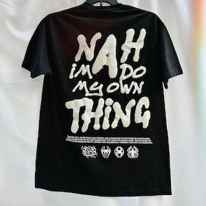 May include: Black t-shirt with white text that reads "NAH IM DO MY OWN THING". The shirt also features a small graphic of a spider web and four spider symbols.