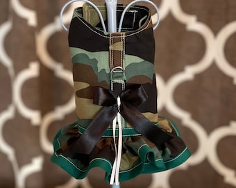 May include: Camouflage dog dress with a black bow and green ruffle trim.