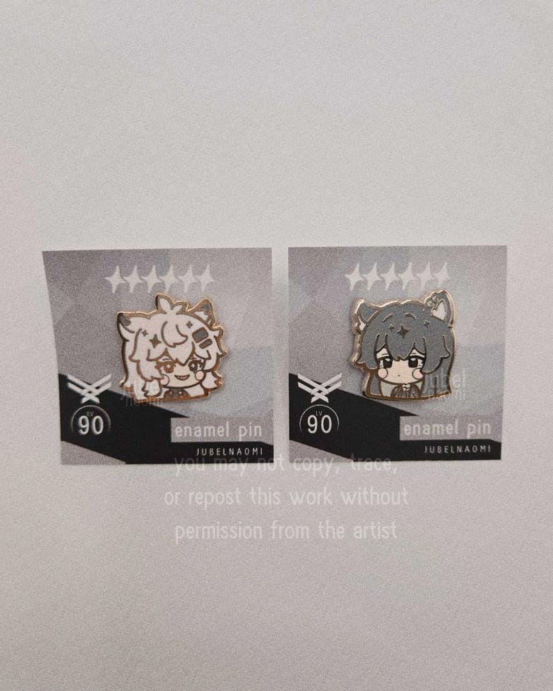 May include: Two enamel pins featuring anime-style characters with gold accents. One pin has a light-colored character, the other a gray character. Each pin is on a gray card with text that reads "enamel pin" and "JUBELNAOMI".