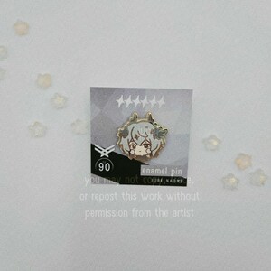May include: An enamel pin featuring a cartoon character with light brown hair and a neutral expression. The pin is on a card with text that reads "enamel pin" and "90". The card also includes text that says "you may not or repost this work without permission from the artist."