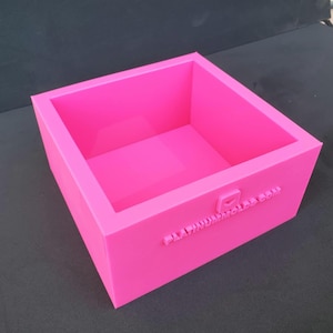 May include: A bright pink silicone mold for making square-shaped crafts. The mold is made by Platinum Molds.