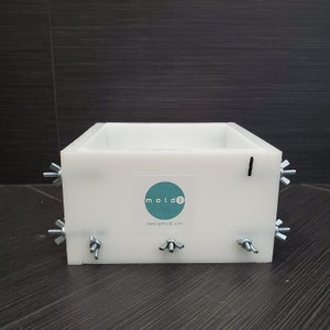 May include: White plastic mold with metal clamps and a blue and white sticker that says "mold1" and "www.getmolds.com".