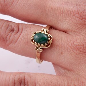 May include: A gold ring with a green oval malachite gemstone set in a delicate filigree design.