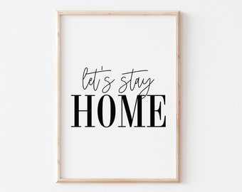 May include: A white framed print with the text "Let's stay HOME" in black lettering. The print is on a white wall.