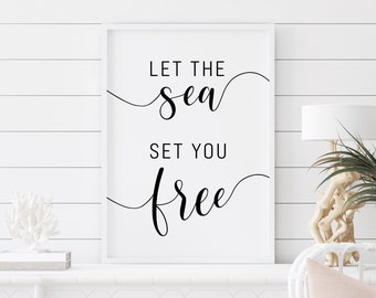 May include: White framed print with black calligraphy that reads "Let the sea set you free".