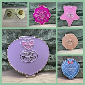 May include: A selection of enamel pins featuring Polly Pocket designs. The pins include flower, star, heart, and shell shapes, each with the Polly Pocket logo. The pins are in shades of pink, purple, and blue with gold accents. Two additional pins are also shown.