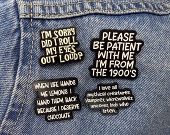 May include: Four black and white enamel pins with humorous phrases. The pins include phrases like "I'm sorry did I roll my eyes out loud?" and "Please be patient with me I'm from the 1900's."