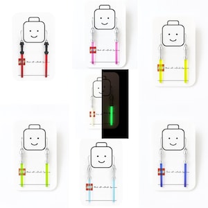 May include: Lightsaber-themed earrings in red, pink, yellow, green, and blue. Each pair is presented on a white card with a smiling Lego-style face. The earrings are made with authentic Lego bricks.