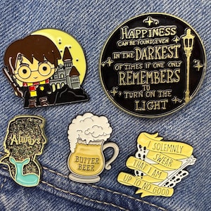 May include: Five enamel pins with Harry Potter designs. Includes Harry with a wand, a castle, a quote about happiness, a stag, a Butterbeer mug, and a banner reading "I solemnly swear that I am up to no good."