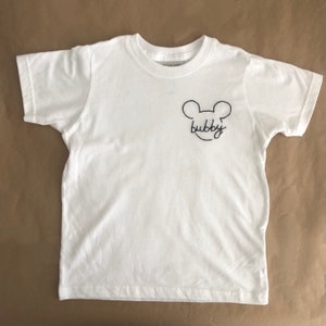 May include: White t-shirt with a black embroidered Mickey Mouse head and the word "bubby" underneath.