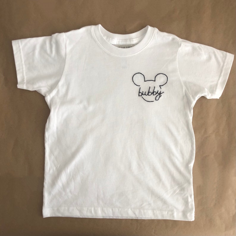 May include: White t-shirt with a black embroidered Mickey Mouse head and the word "bubby" underneath.