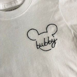 May include: White t-shirt with black embroidered Mickey Mouse ears and the word "bubby" underneath.