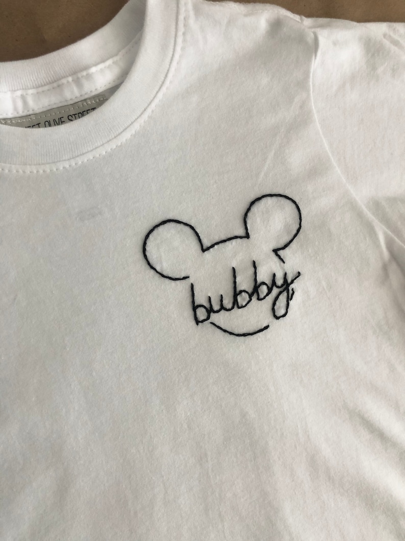 May include: White t-shirt with black embroidered Mickey Mouse ears and the word "bubby" underneath.