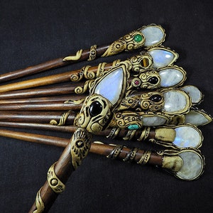 May include: A set of ten wooden hair sticks with intricate carvings and gemstone accents. Each stick features a different gemstone, including moonstone, turquoise, and onyx. The sticks are a beautiful and unique way to style hair.