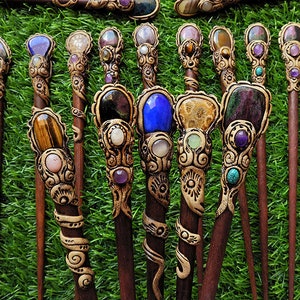 May include: A set of 10 wooden hair sticks with decorative gemstone tops. The sticks are brown and the tops are adorned with various coloured gemstones, including blue, green, purple, and brown.