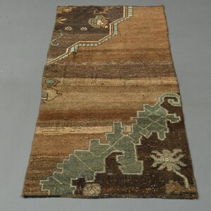May include: A brown and blue vintage rug with a geometric pattern. The rug has a faded look and is made of wool.
