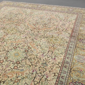 May include: A beige rug with a floral pattern and a border of intricate designs in shades of pink, green, and brown.