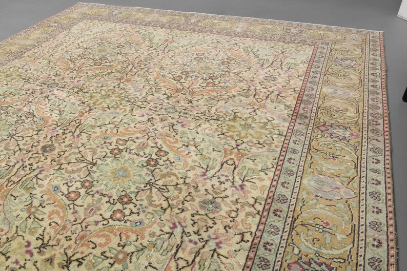 May include: A beige rug with a floral pattern and a border of intricate designs in shades of pink, green, and brown.