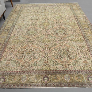 May include: A vintage Persian rug with a cream background and intricate floral patterns in shades of pink, green, and brown. The rug has a border with a repeating design of stylized flowers and leaves.