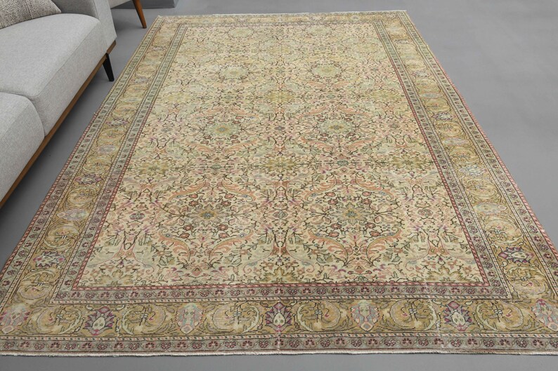 May include: A vintage Persian rug with a cream background and intricate floral patterns in shades of pink, green, and brown. The rug has a border with a repeating design of stylized flowers and leaves.