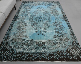 Puede incluir: Una alfombra de estilo vintage con un patrón floral azul y negro. La alfombra tiene un aspecto desgastado y es perfecta para añadir un toque de estilo bohemio a cualquier habitación.