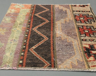 May include: A colorful vintage rug with a geometric pattern in shades of red, brown, beige, and green. The rug has a fringed edge and is made of woven fabric.