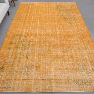 Könnte beinhalten: Ein Vintage-Teppich mit einem verblassten orangen Hintergrund und einem dezenten floralen Muster in einem helleren Orangeton. Der Teppich hat einen abgenutzten Look, der ihm ein rustikales und antikes Aussehen verleiht.