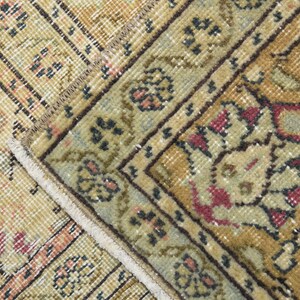 May include: Close-up of a beige and brown patterned rug with a fringe border. The rug has a floral design with red, blue, and green accents.