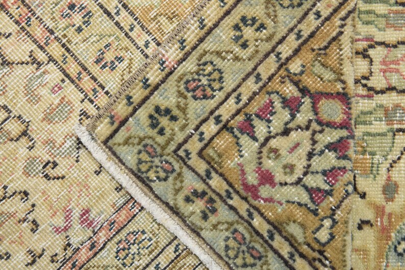 May include: Close-up of a beige and brown patterned rug with a fringe border. The rug has a floral design with red, blue, and green accents.