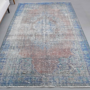 Könnte beinhalten: Ein Vintage-Teppich mit einem verblassten blauen und roten Muster. Der Teppich hat einen abgenutzten Look und ist aus Wolle.