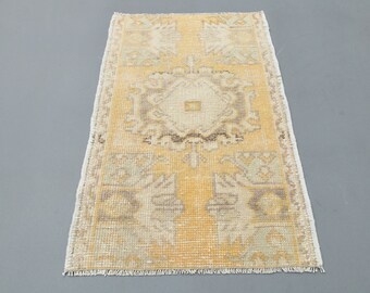 Puede incluir: Una alfombra pequeña y rectangular de color beige y amarillo. La alfombra tiene un medallón central con un diseño geométrico y un borde con flecos.
