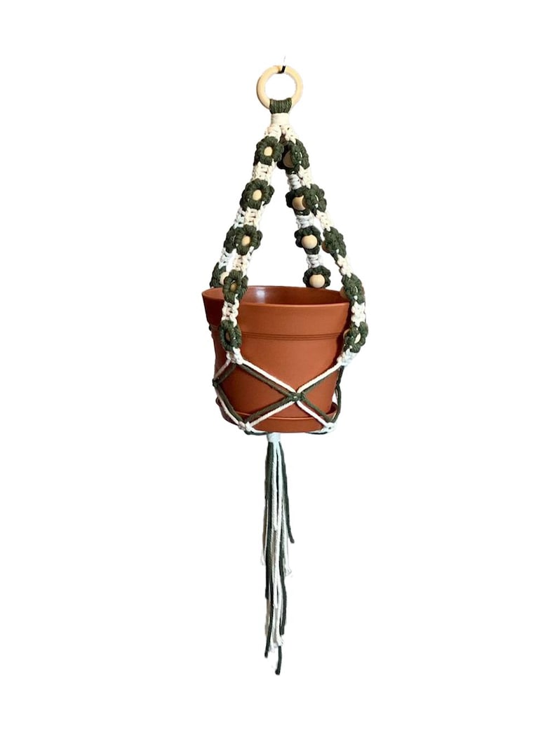 Peut inclure: Un porte-plante en macram&eacute; blanc et vert avec des perles en bois et un pot en terre cuite. Le porte-plante a une boucle en haut pour l'accrocher.