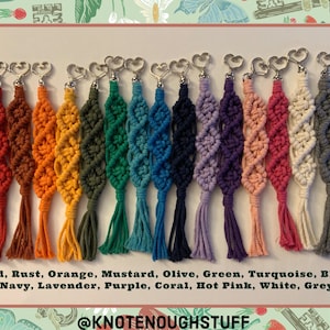 Puede incluir: Una colecci&oacute;n de 15 llaveros de macram&eacute; de colores con anillos met&aacute;licos en forma de coraz&oacute;n. Los llaveros est&aacute;n hechos de una variedad de colores, incluyendo rojo, &oacute;xido, naranja, mostaza, oliva, verde, turquesa, azul, azul marino, lavanda, morado, coral, rosa intenso, blanco y gris. Los llaveros son todos del mismo tama&ntilde;o y forma, y est&aacute;n dispuestos en una fila sobre un fondo blanco. El texto "@KNOTENOUGHSTUFF" est&aacute; escrito debajo de los llaveros.