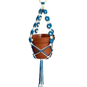 Peut inclure: Un porte-plante en macram&eacute; blanc et turquoise avec des perles en bois et un pot en terre cuite.